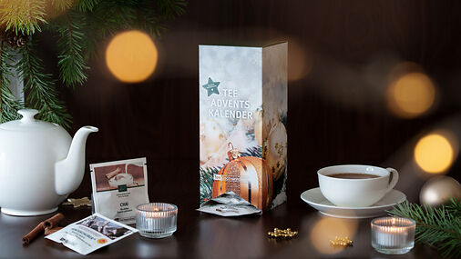 Tee-Adventskalender,Teekanne und Teetasse auf dunklem Untergrund, dekortiert mit Tannenzweigen